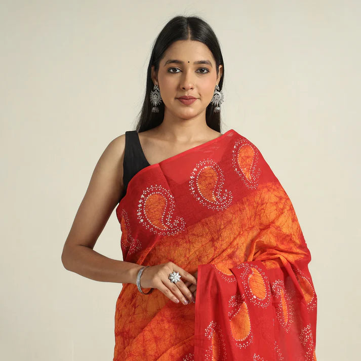 Plumvera model wearing red orange hand batik cotton saree with paisley motifs and silver jhumka earrings