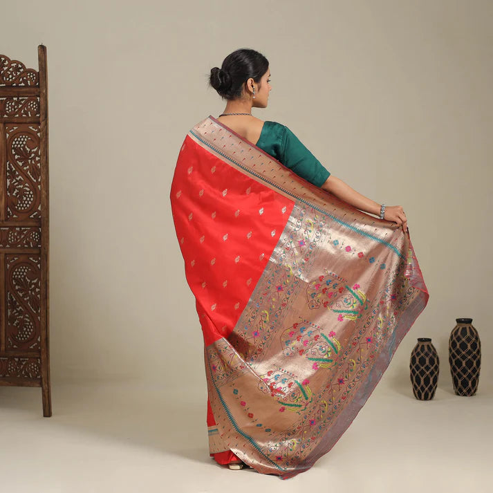 Woman modeling red pure silk paithani saree with gold zari pallu and green blouse back pose
