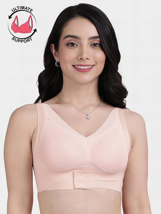 Smiling model wearing a peach front hook seamless bra with V neck wide straps and supportive band