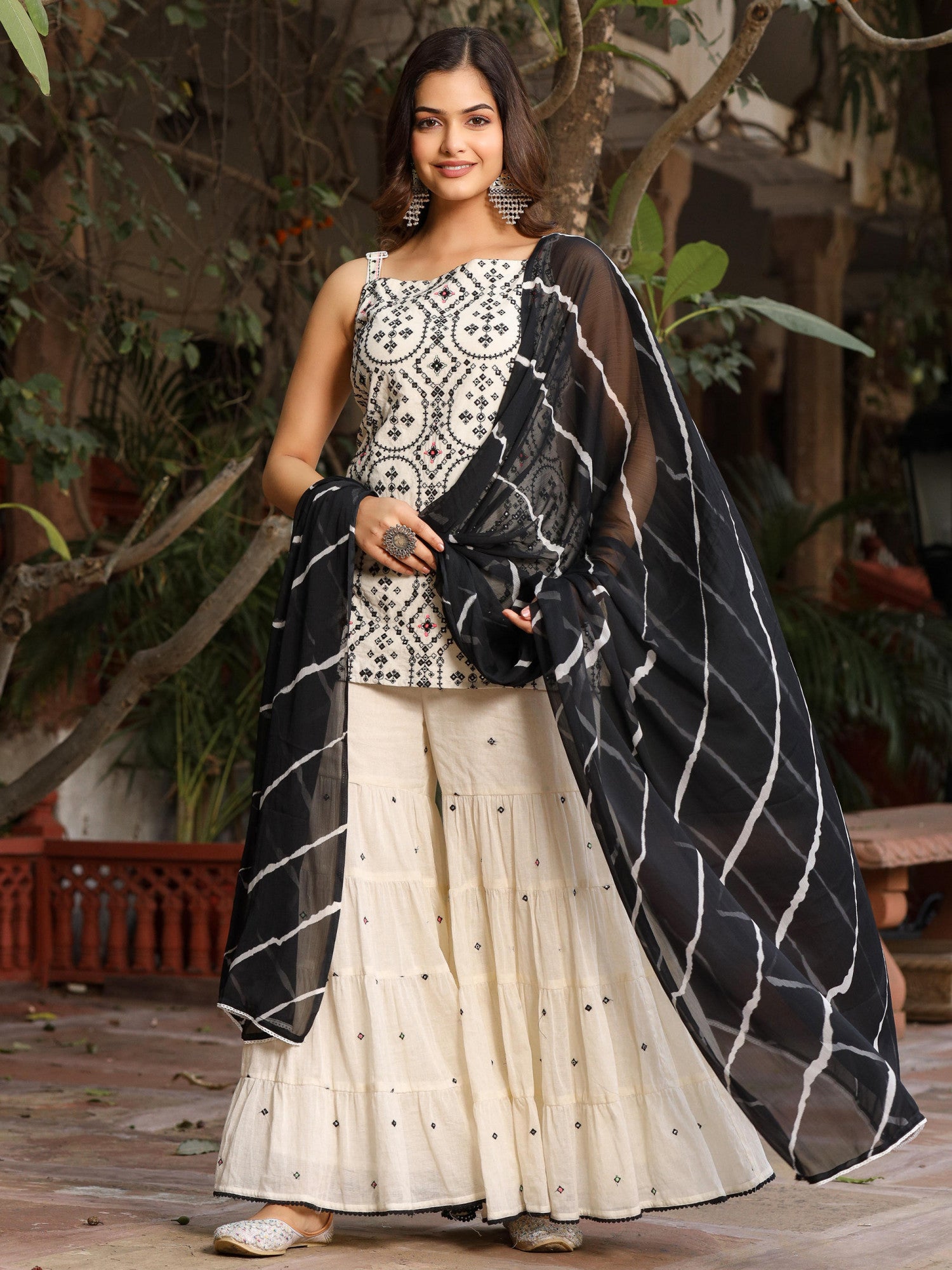 Model wearing Juniper off-white and black embroidered sharara set with embroidered top and black striped dupatta