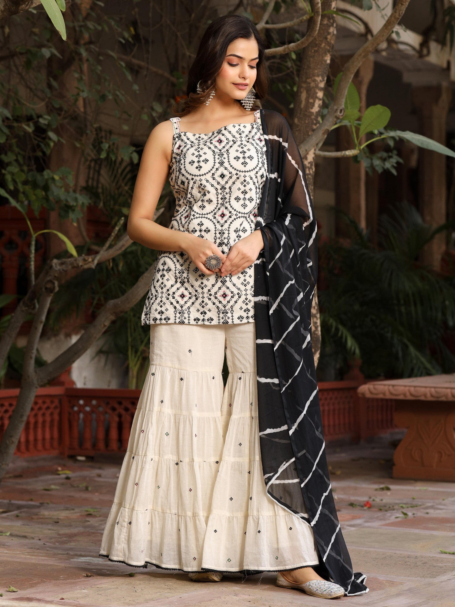 Model wearing Juniper off-white and black embroidered sharara set with sleeveless embroidered kurta and black patterned dupatta